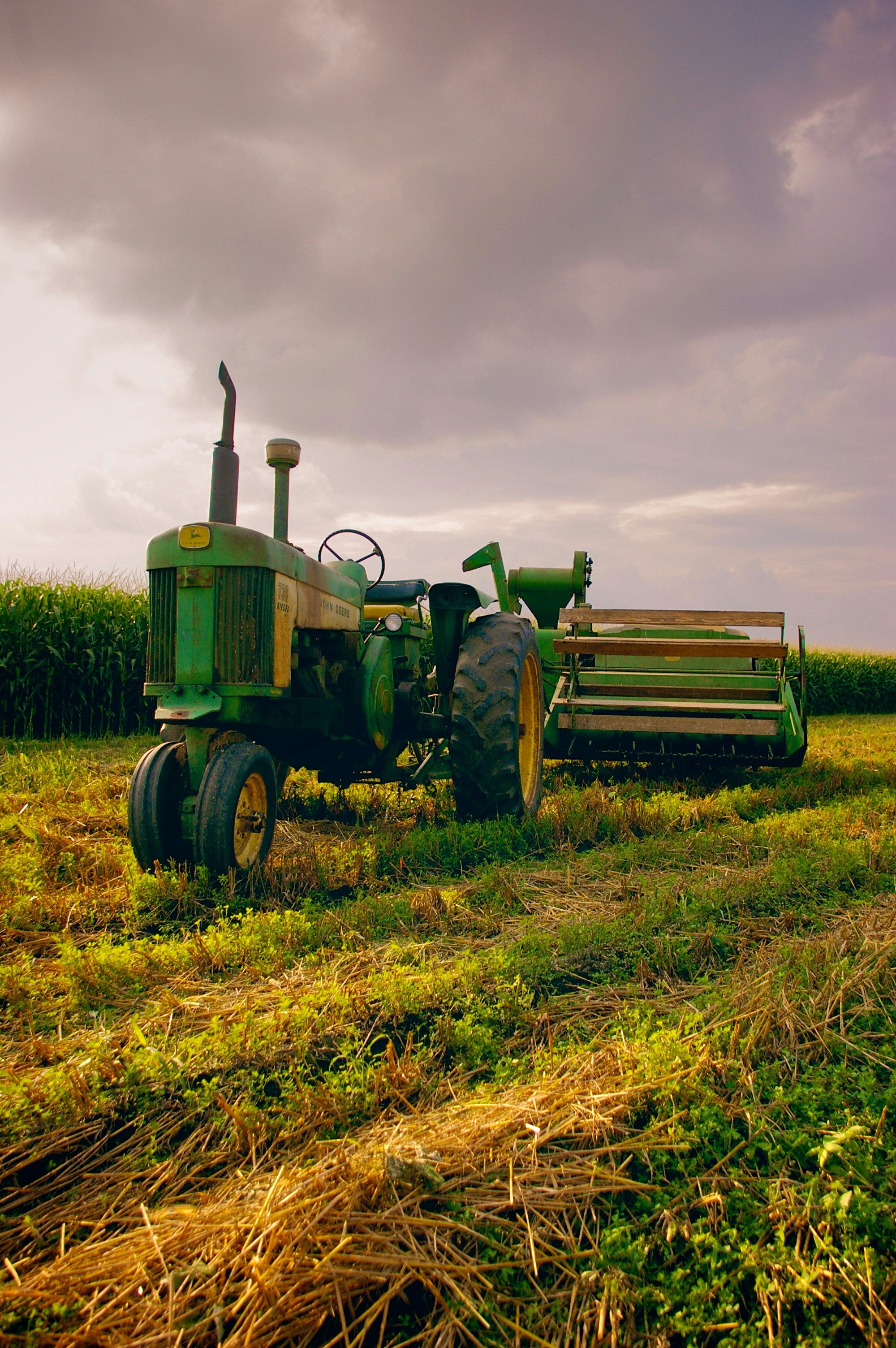 Green tractor in a field with a stormy sky