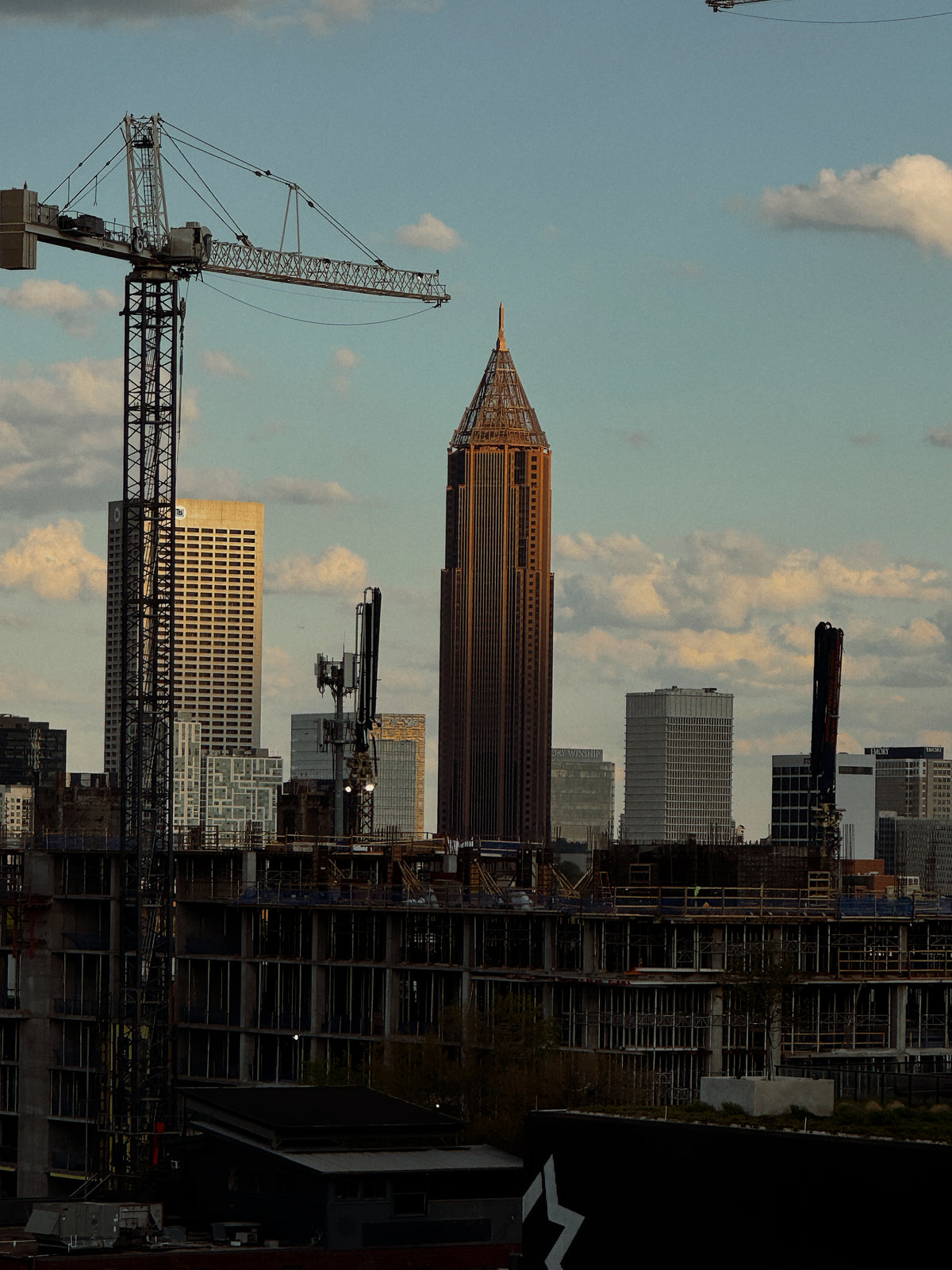City skyline with tall buildings and cranes against a cloudy sky