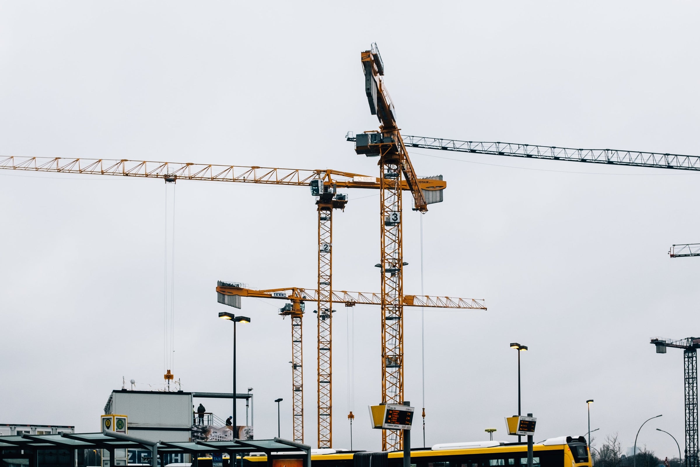 Bus stop with yellow buses and construction cranes in the background