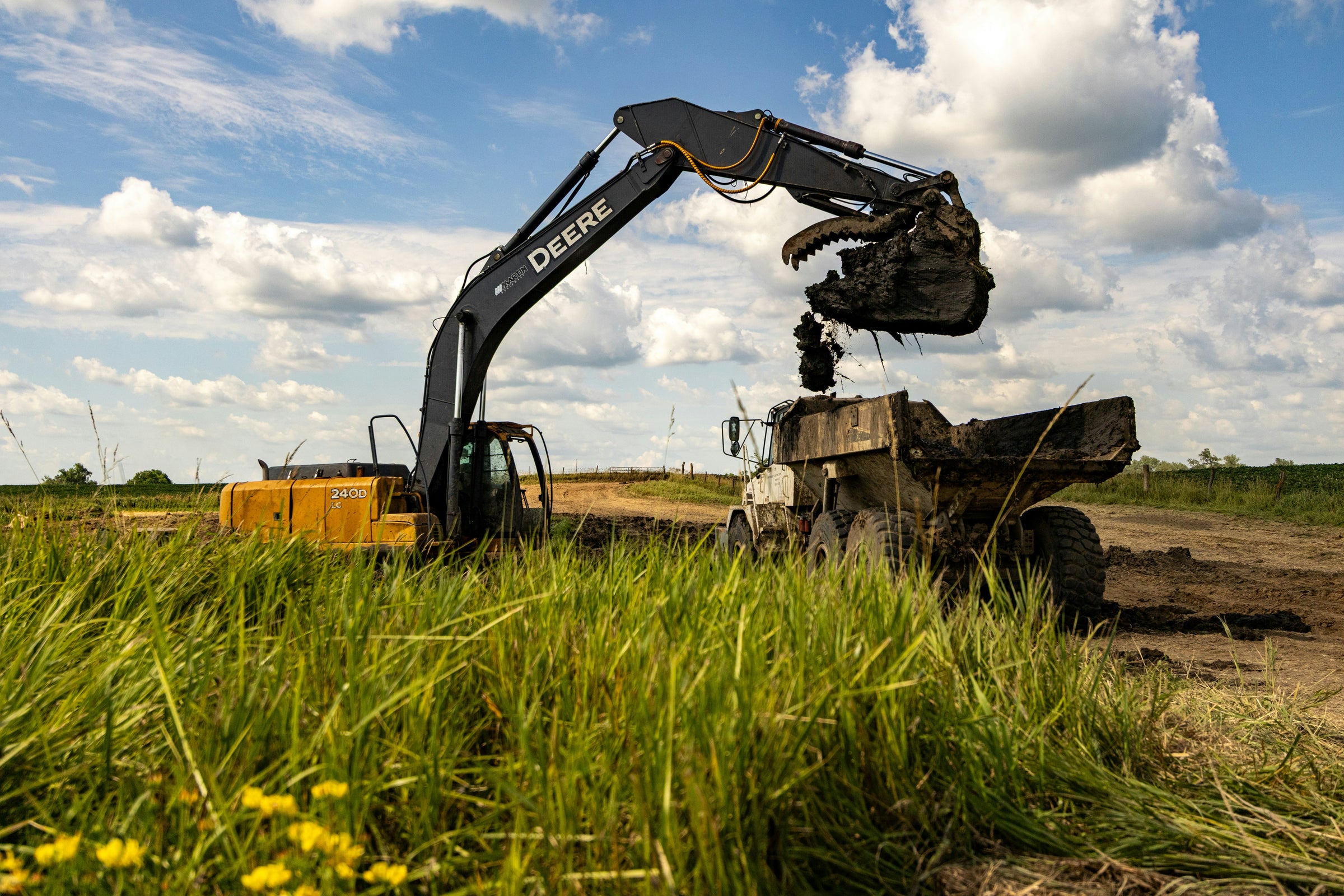 John Deere Machine filling a dump truck on a construction site.